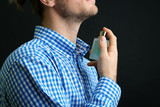 Fototapeta  - Handsome young man using perfume on black background