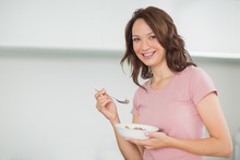 Portrait Of Smiling Woman With A Bowl Of Cereals At Home