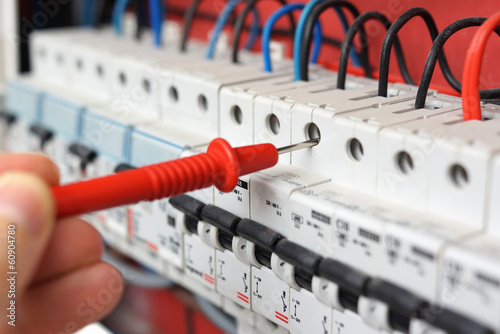 Fotografía Hand of an electrician with multimeter probe at an electrical sw