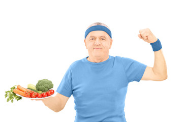 Poster - Mature man holding plate full of vegetables and showing strength