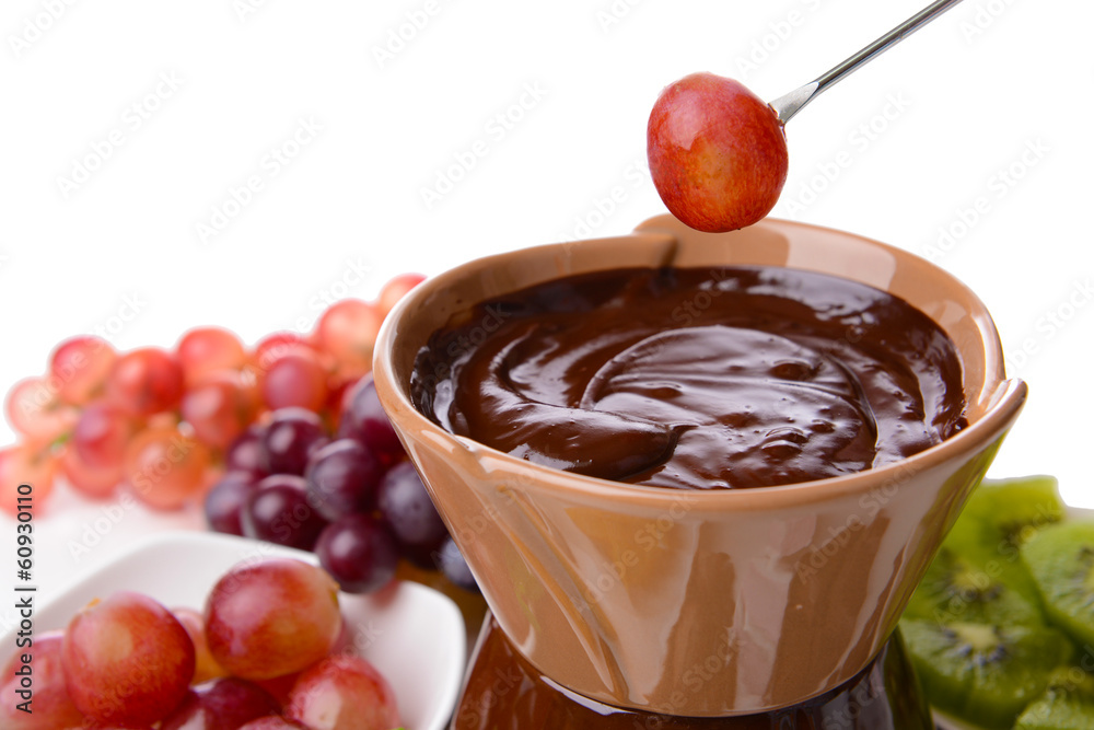 Chocolate fondue with sliced fruits, isolated on white