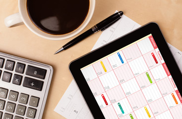 Wall Mural - tablet pc showing calendar on screen with a cup of coffee on a d