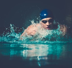 Wall Mural - Muscular young man in blue cap in swimming pool