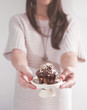 © NKMandic - Young woman holding a muffin with chocolate and almonds