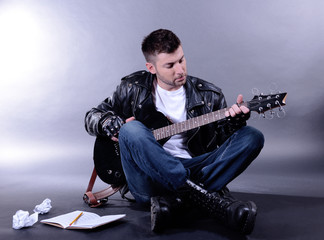 Wall Mural - Young musician playing  guitar on gray background