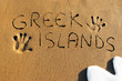 Greek islands written on sandy beach