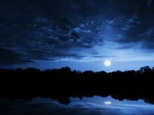 Dramatic Moonrise With Deep Blue Sky Lake Reflections And Clouds