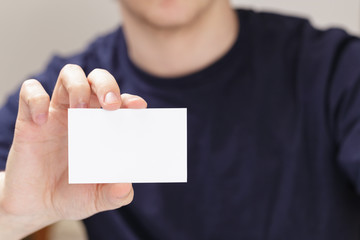 Wall Mural - adult man hand holding empty business card in front of camera