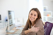 © goodluz - Smiling woman in office sitting at desktop