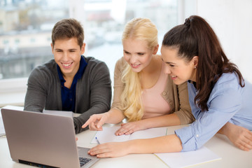 Wall Mural - three smiling students with laptop and notebooks