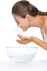 Wall Mural - Profile portrait of woman washing face in glass bowl with water