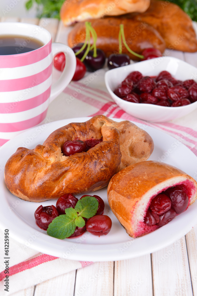 Fresh baked pasties with cherry on plate on table close-up