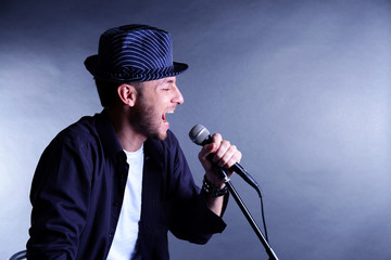 Wall Mural - Young musician singing, on gray background