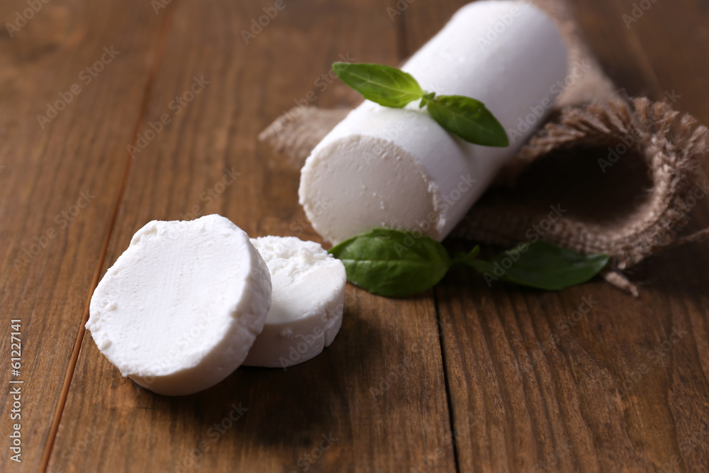 Tasty bushe cheese with basil, on wooden table