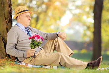 Sticker - Senior man with flowers sitting on grass, checking the time