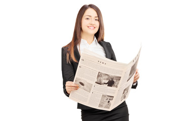 Wall Mural - Young businesswoman in suit leaning on wall with a newspaper