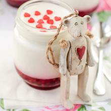 Teddy Bear Toy Leaning Over A Jar Of Yoghurt With Raspberry Jam