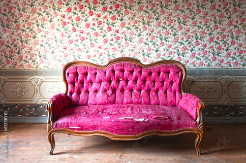 Fotografía Old damaged red couch in an antique house. Flowers wallpaper