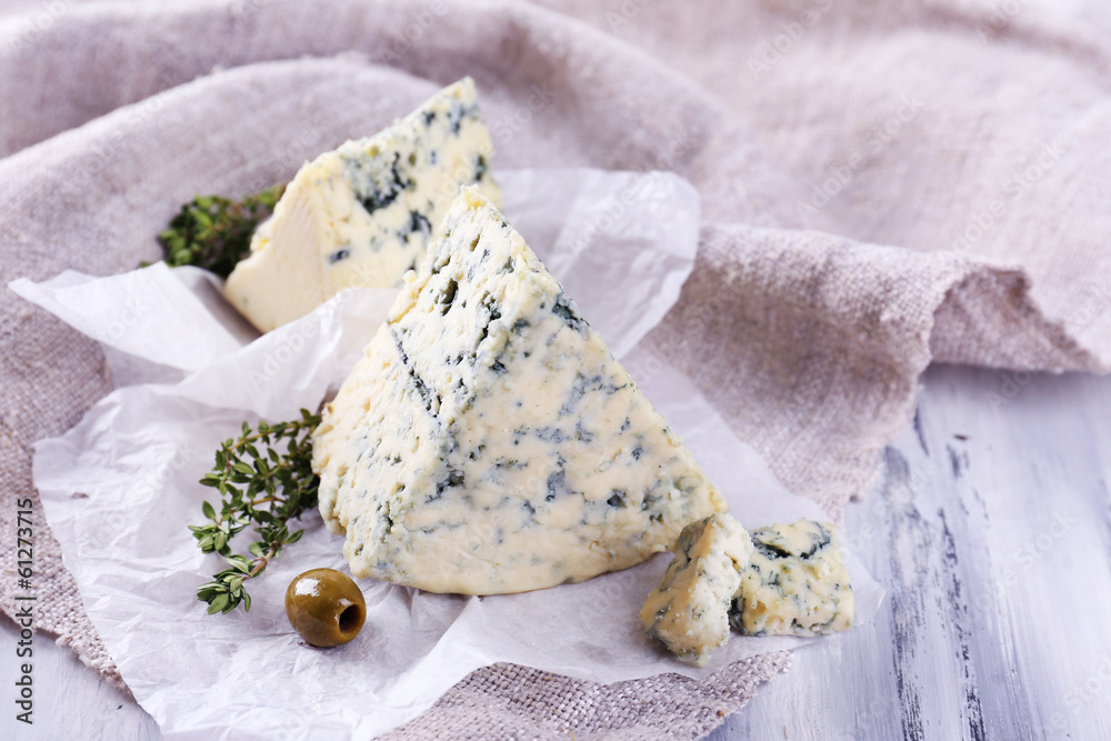 Tasty blue cheese with thyme and olives on paper