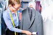 Textilreinigerin  in Wäscherei kontrolliert Kleidung 