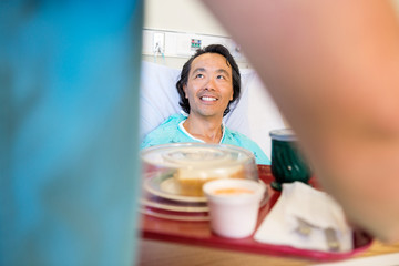 Wall Mural - Happy Patient Looking At Nurse Serving Breakfast