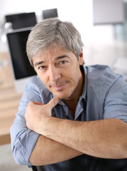 Wall Mural - Smiiling mature man relaxing in office chair