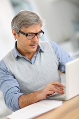 Wall Mural - Senior businessman in office working on laptop