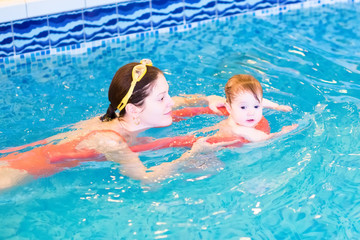 Wall Mural - Young mother with a little baby in the swimming pool