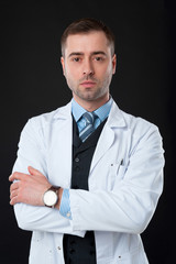 Mature Serious male doctor with crossed arms isolated on black b