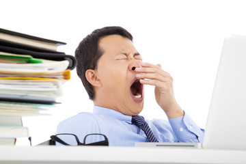 Wall Mural - Exhausted young businessman yawning at work