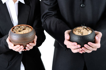 Two ceramic pots with golden coins in male and female hands,