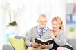 © Ljupco Smokovski - Mature couple reading a book seated on couch, at home