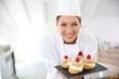 © goodluz - Smiling pastry chef showing desserts on plate