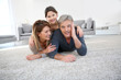 © goodluz - Middle-aged couple with little girl laying on carpet