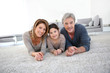 © goodluz - Middle-aged couple with little girl laying on carpet