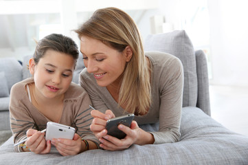 Wall Mural - Mother and daughter playing games with smartphone