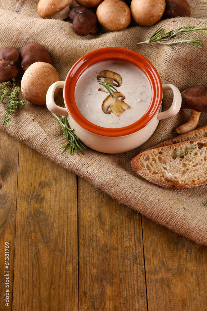 Mushroom soup in pot, on wooden background