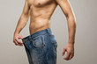 Muscular fit man wearing big jeans after diet