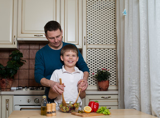 father and his son preparing a salad in the kitchen.