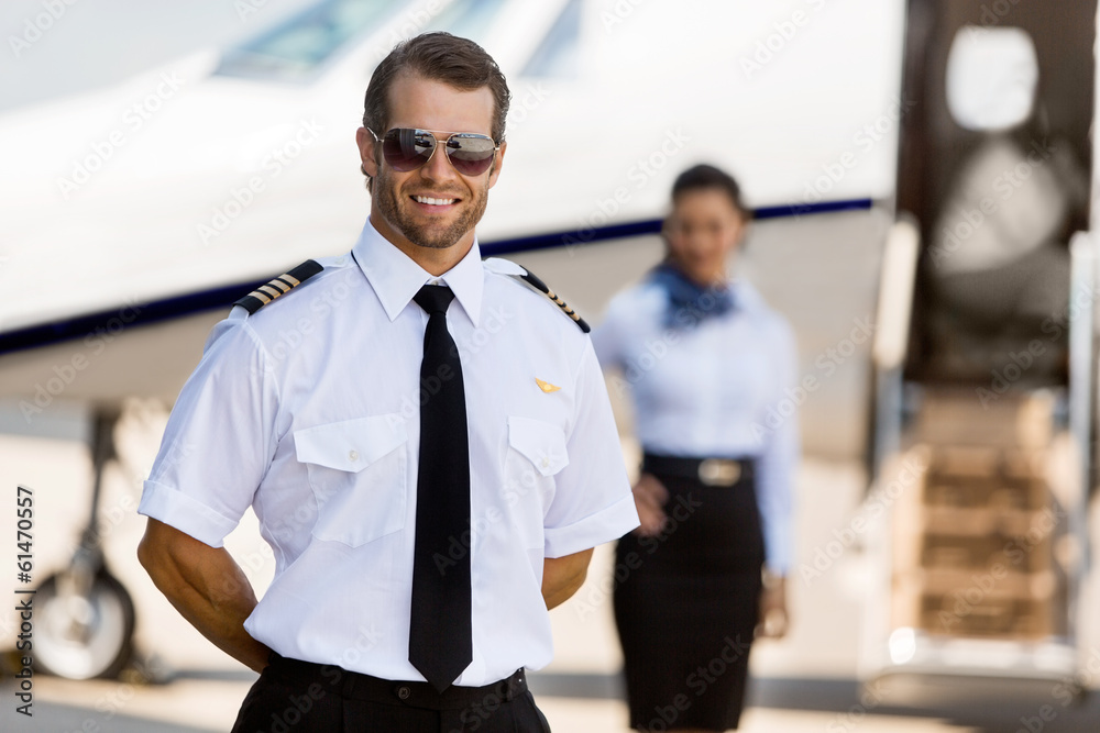 Pilot Standing With Stewardess And Private Jet At Terminal - obrazy, fototapety, plakaty 