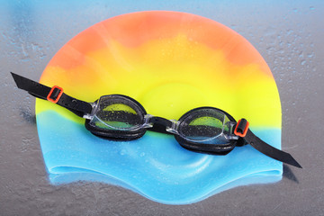 Wall Mural - Swim cap and goggles on silver background