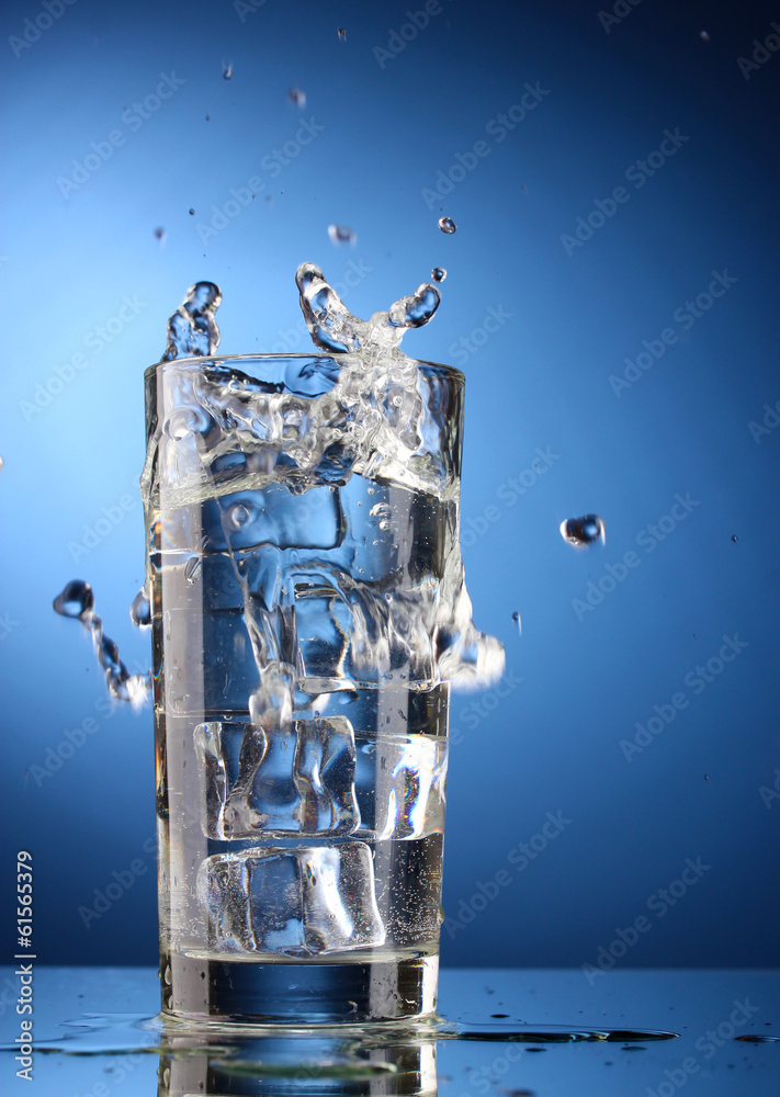 fresh water in glass with ice cubes on blue background
