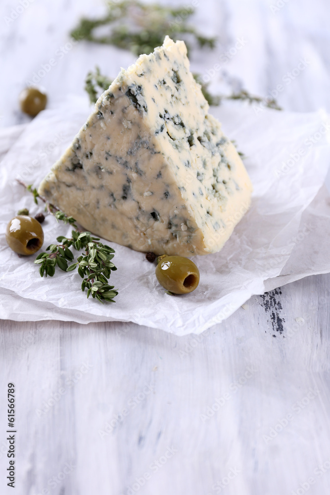 Tasty blue cheese with thyme and olives on wooden table