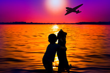 Silhouette Of Boy And Dog At Sunset Watching Aircraft