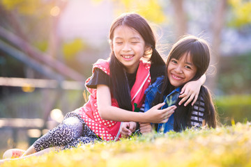 Children girls hug in green grass park, Outdoor