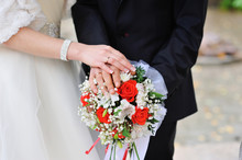 Hands Of The Bride And Groom With Rings On A Wedding Bouquet