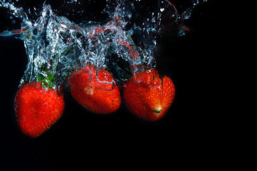 Wall Mural - fresh strawberry dropped into water with splash on black backgro