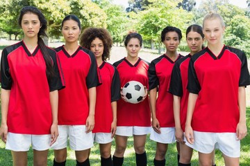 Female soccer team with ball at park