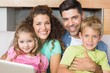 © WavebreakmediaMicro - Happy family sitting on sofa with laptop