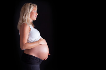 Pregnant woman touching her belly with hands. Isolated over a bl